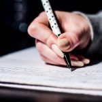 Рука з ручкою пише в зошиті — як правильно писати по батькові Борисівна