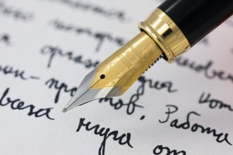 Рука пише чорнилом у зошиті — як правильно написати по батькові Олексіївна