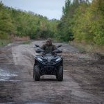Військовий ЗСУ їде ґрунтовою дорогою на квадроциклі